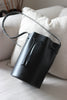Geöffnete schwarze Beuteltasche aus Leder auf einem beigen Sofa