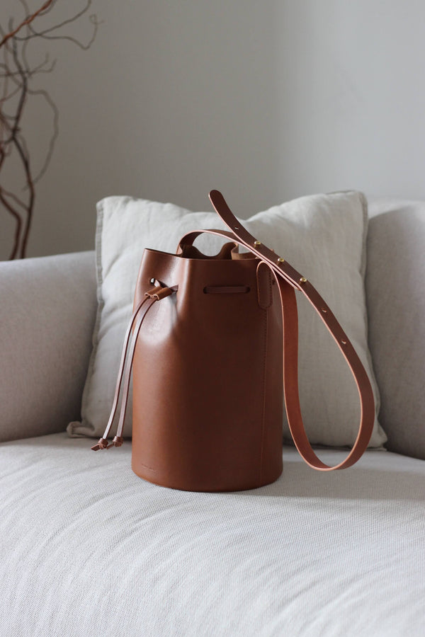 Braune Bucket Bag aus Leder auf einem beigen Sofa im Wohnzimmerambiente