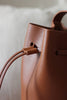 Detailaufnahme des Kordelstoppers an der braunen Bucket Bag