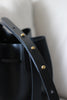 Detailaufnahme des Lederriemens mit Messing-Patronenverschlüssen an der schwarzen Bucket Bag