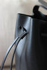 Detailaufnahme des Kordelstoppers an der schwarzen Bucket Bag